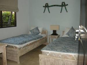a room with two beds and a table and a lamp at Villa Jasri Point - Beachfront Villa close to surf in Jasri