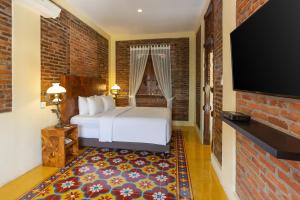 a hotel room with a bed and a flat screen tv at Bale Devata Resort in Sleman