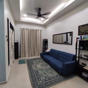 uma sala de estar com um sofá azul e uma ventoinha de tecto em Desa Hana Homestay em Kuala Terengganu