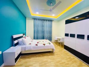 a bedroom with a white bed and a blue wall at Hedheykuri Residence Fuvahmulah in Fuvahmulah