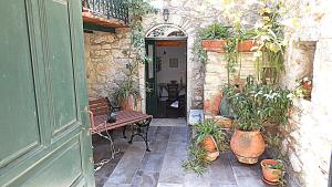 an outdoor patio with a bench and potted plants at Karampela Despina in Mestá
