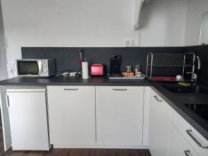 a kitchen with white cabinets and a microwave at La Maison de Soso in Chambon-le-Château