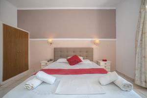una camera da letto con un grande letto bianco con cuscini rossi di ALADDIN TSILLIVi a Tsilivi