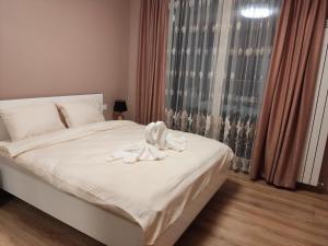 a bedroom with a bed with white sheets and a window at Mountain view apartment in Sofia