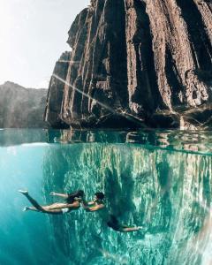 two people swimming in the water near a rock formation at Maleez Lodge in Pattaya Central