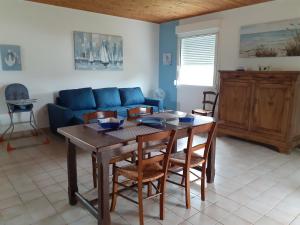 uma sala de estar com uma mesa e um sofá azul em Maison vacances d'Oléron em La Brée-les-Bains