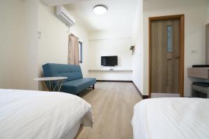 um quarto com duas camas e uma cadeira azul em 享悅二館電梯民宿 em Magong