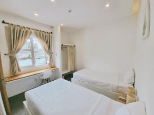 a bedroom with two beds and a window at LaDa's House Da Nang in Danang