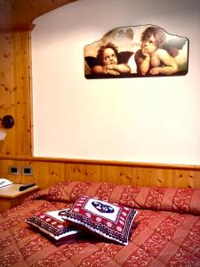 ein Bett mit zwei Kissen und einem Gemälde an der Wand in der Unterkunft Hotel Moderno Restaurant in Serina