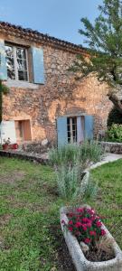 a stone house with flowers in front of it at Gîte Les Fourches in Baudinard
