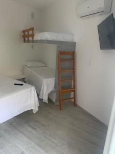 Cette chambre dispose de deux lits, d'une télévision et d'une échelle. dans l'établissement Apartamentos de Juan, à Morro de São Paulo