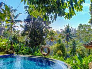 a swimming pool in the middle of a tropical garden with trees at Made Punia's Jungle in Ubud