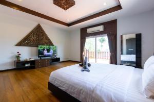 a bedroom with a large white bed and a television at 5 Bedroom Pool Villa Close To Town H5 in Hua Hin