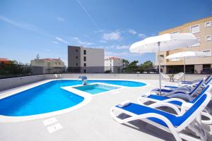 a swimming pool with lounge chairs and an umbrella at Stella Maris in Promajna