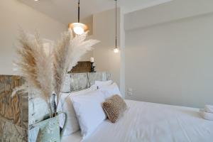 1 dormitorio con cama blanca con almohadas blancas y plumas en Monastiraki #507 by SuperHost Hub AcropolisView en Athens