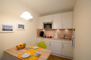 eine Küche mit weißen Schränken und einem Tisch mit Obst darauf in der Unterkunft Haus Therese *FeWo 14* in Wittdün
