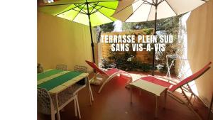 een restaurant met een tafel, stoelen en parasols bij Le Bijou Appartement avec Jacuzzi et Sauna privatif Terrasse plein sud Clim Parking Privatif in Bandol