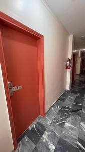 a red door in a hallway with a tile floor at Hotel Cosmos in Athens