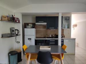 a kitchen with a table and yellow chairs in it at Gîte La p'tite terrasse Chinon centre in Chinon