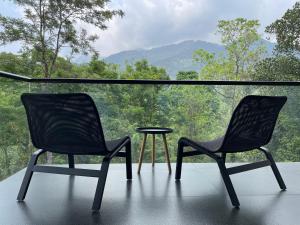 two chairs and a table in front of a window at Flora Vythiri Resort in Vythiri
