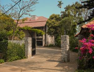 a driveway leading to a house with a gate and flowers at Flora Vythiri Resort in Vythiri