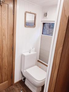 een kleine badkamer met een toilet en een raam bij Relaxing retreat for 2 on beautiful converted bus in Levaré