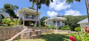 a white house with a palm tree in the yard at La Trouvaille in Anse a La Mouche