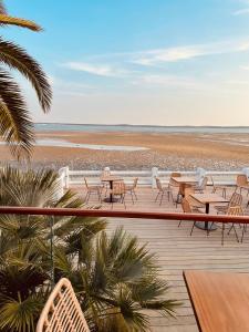 a deck with tables and chairs on the beach at Hôtel L'Albatros in Saint-Trojan-les-Bains