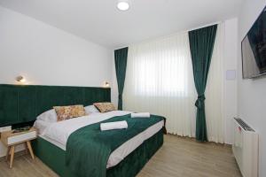 a bedroom with a large bed with a green headboard at Stella Maris in Promajna