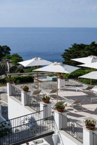 a patio with white umbrellas and chairs and the ocean at La Residenza Capri in Capri