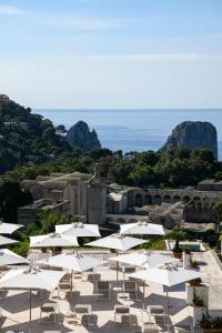 een groep witte parasols en stoelen en de oceaan bij La Residenza Capri in Capri