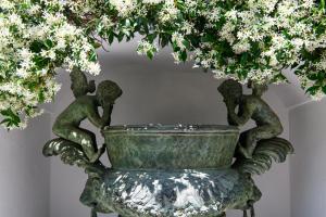 a statue of three cherubs in a fountain with flowers at La Residenza Capri in Capri