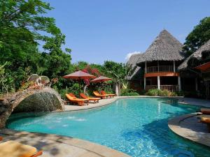 einen Pool in einem Resort mit Stühlen und Sonnenschirmen in der Unterkunft Villa Ndoto in Diani Beach