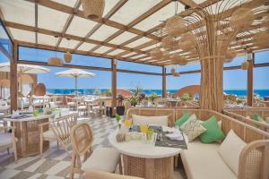 The Boutique Hotel Hurghada Marina في الغردقة: مطعم به طاولات وكراسي والمحيط في الخلف