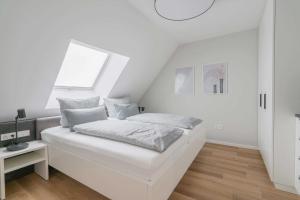 um quarto branco com uma cama e uma janela em Haus Harmening Whg 4 em Norderney