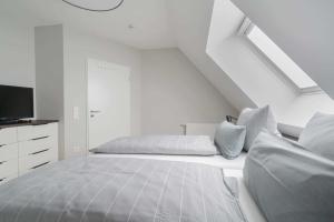 um quarto branco com uma cama e uma televisão em Haus Harmening Whg 4 em Norderney