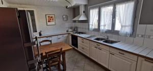 a kitchen with white cabinets and a wooden table in it at Logement hyper centre Champagnole (jura) in Champagnole
