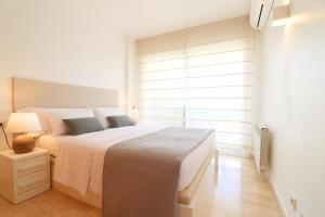 a white bedroom with a large bed and a window at A&A Brothers Port d'Aro in Platja d'Aro