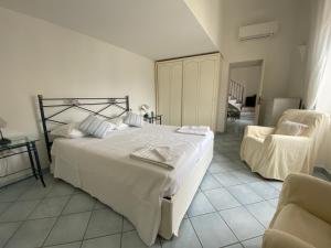 um quarto com uma grande cama branca e uma cadeira em Regina di Capri - Sopramonte - em Capri