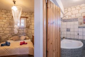 a bathroom with a tub and a bed and a bath tub at Gerakomylos Stone House in Vasilikos