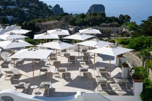 a group of white umbrellas and chairs and the ocean at La Residenza Capri in Capri