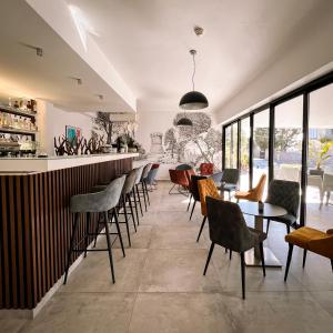 a restaurant with a bar with chairs and tables at Hotel l'Isolella in Porticcio