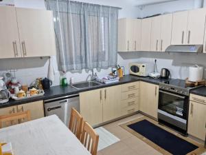 a kitchen with white cabinets and a table in it at LiriKa's airport house in Artemida +18 photos