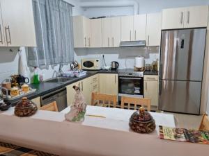 a kitchen with white cabinets and a counter with a table at LiriKa's airport house in Artemida
