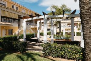 a white pergola in front of a building at Townhouse with terraces and communal pool in Gandía