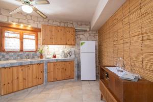 a kitchen with wooden cabinets and a white refrigerator at Gerakomylos Stone House in Vasilikos +20 photos