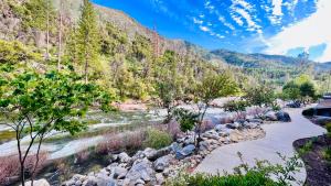a river with rocks and trees next to a mountain at Yosemite View Lodge in El Portal
