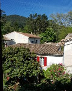 ein weißes Haus mit roten Türen und einem Baum in der Unterkunft Vista Cevenol: appartement 2 chambres in Saint-Jean-du-Gard
