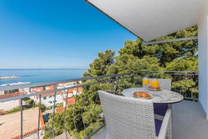 a balcony with a table and two glasses of orange juice at Milka Apartments in Makarska