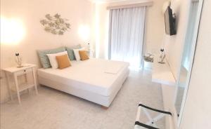 a white bedroom with a bed and a television at Akrogiali in Skala